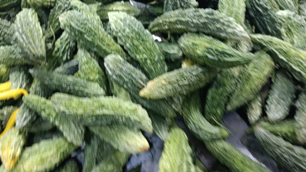 Fresh bitter gourds stacked at a local Karachi vegetable market, showcasing their rugged green texture and cultural significance.